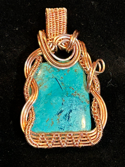 Copper wire wrapped Chrysocolla pendant on black background
