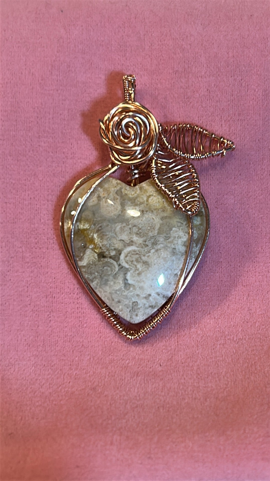 Copper wire wrapped Cotton Candy Agate heart pendant with rose and leaf detail on pink background