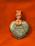Copper wire wrapped teal Amazonite heart pendant with stacked double spiral bail on red-orange background