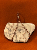 Copper wire wrapped Lace Agate pendant on rust-colored background