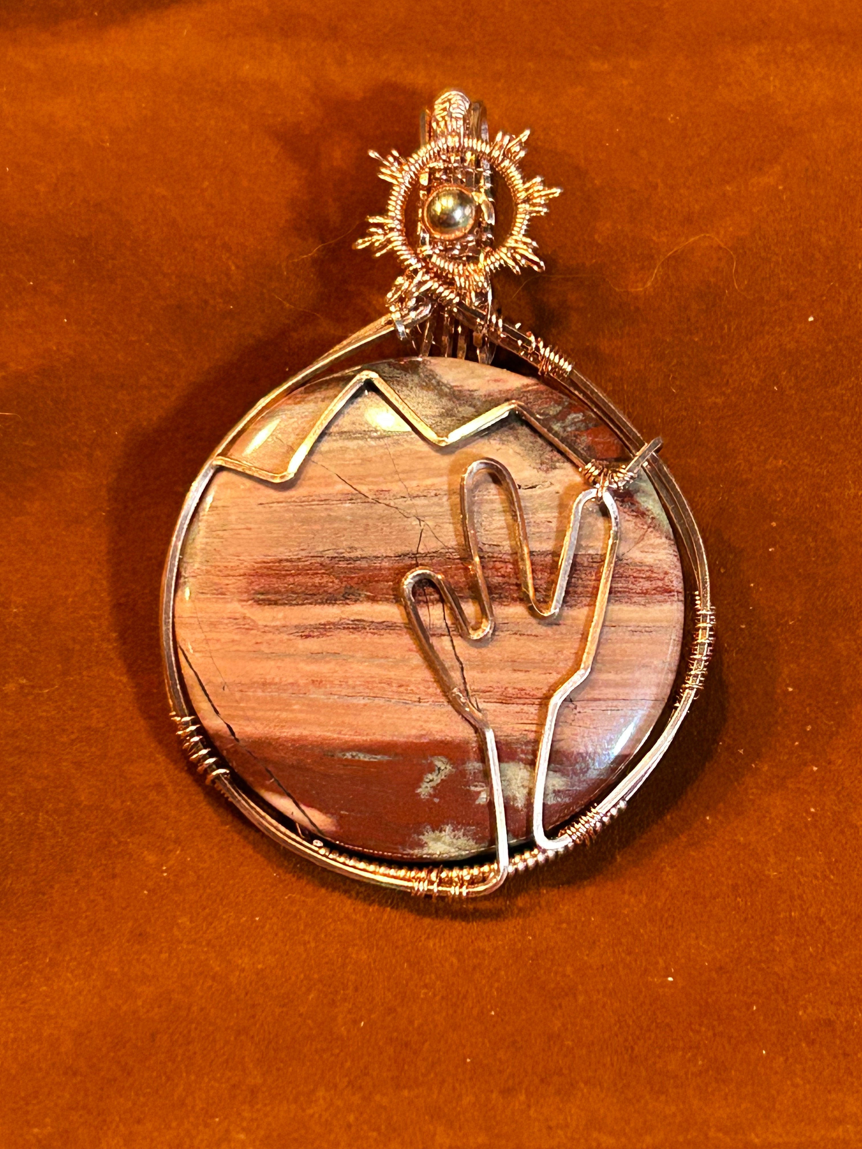 Copper wire wrapped round Jasper pendant with hand-sculpted wire cactus and mountain scene on rust background