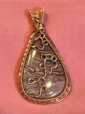 Copper basketweave wire wrapped Imperial Jasper teardrop pendant with two wire paw print details on pink background