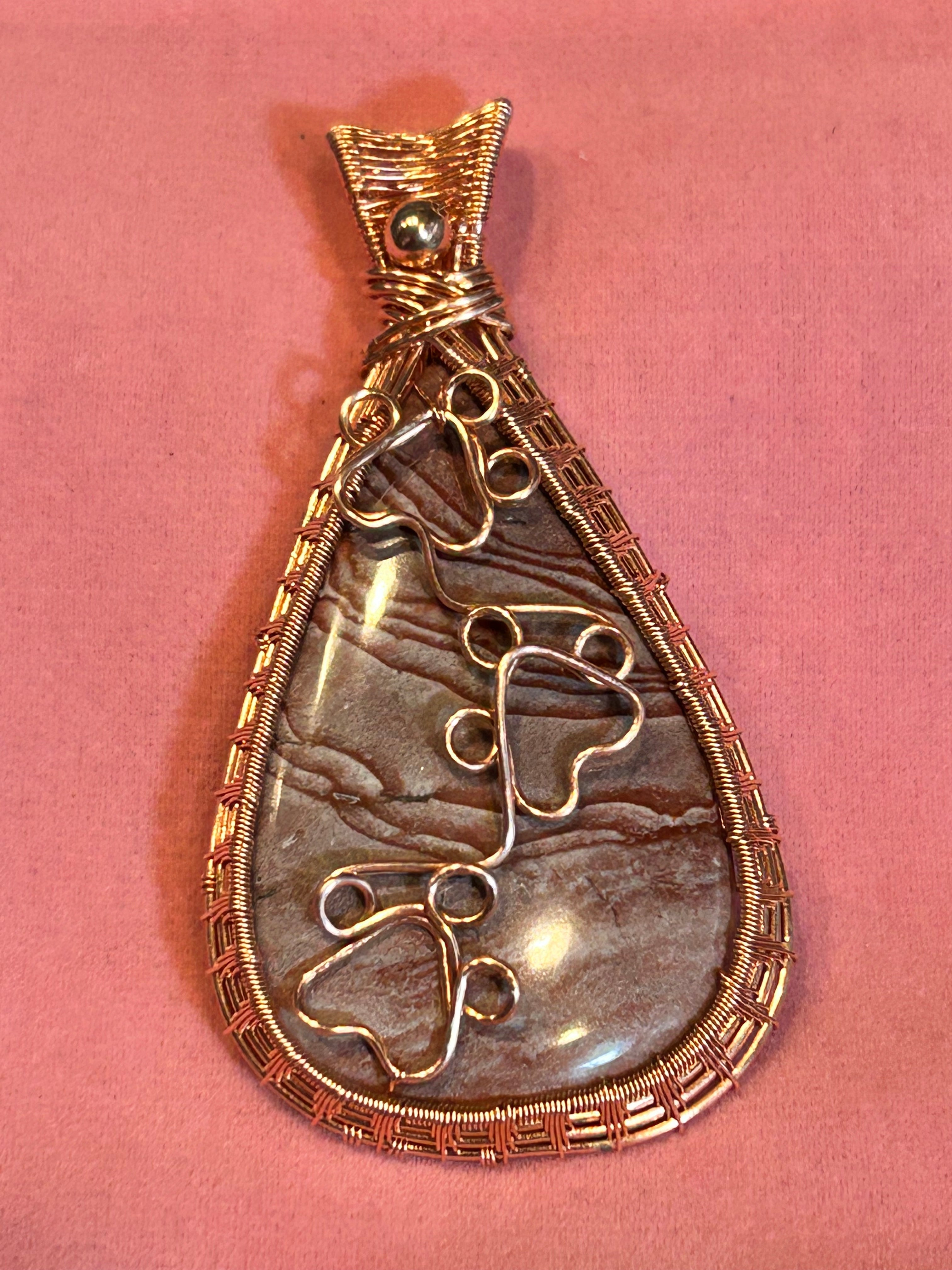 Copper basketweave wire wrapped Imperial Jasper teardrop pendant with two wire paw print details on pink background