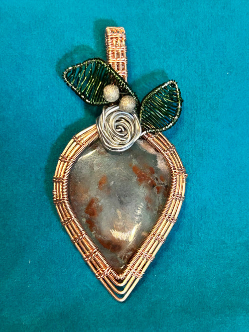 Copper and gold wire wrapped Aquaprase strawberry pendant with green wire leaves and silver rose on teal background