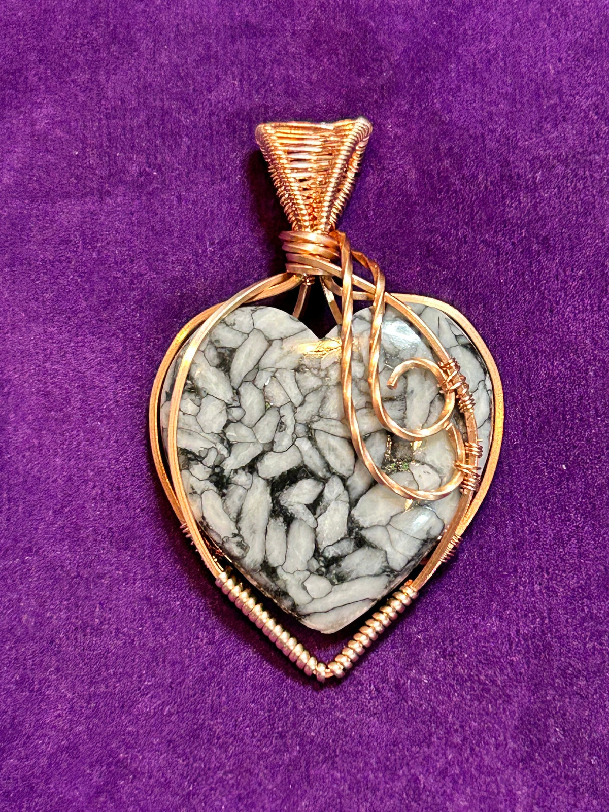 Copper wire wrapped Pisolith heart pendant with scroll accent on purple background