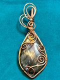 Copper wire wrapped marquise Labradorite pendant with scroll flourishes on teal background