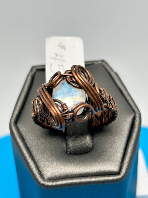Handcrafted oxidized copper wire wrapped Rainbow Moonstone ring, size 9, displayed on a jewelry stand