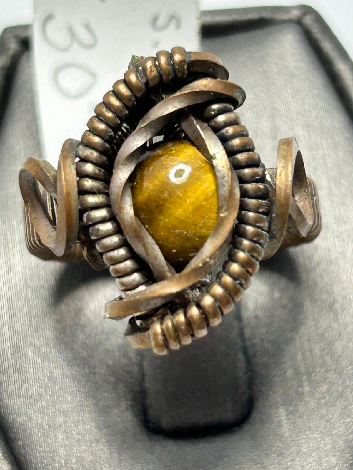 Copper wire wrapped tiger's eye oval cabochon ring size 5 with eye-shaped frame, serrated coiled bezel border, and open spiral curl side accents
