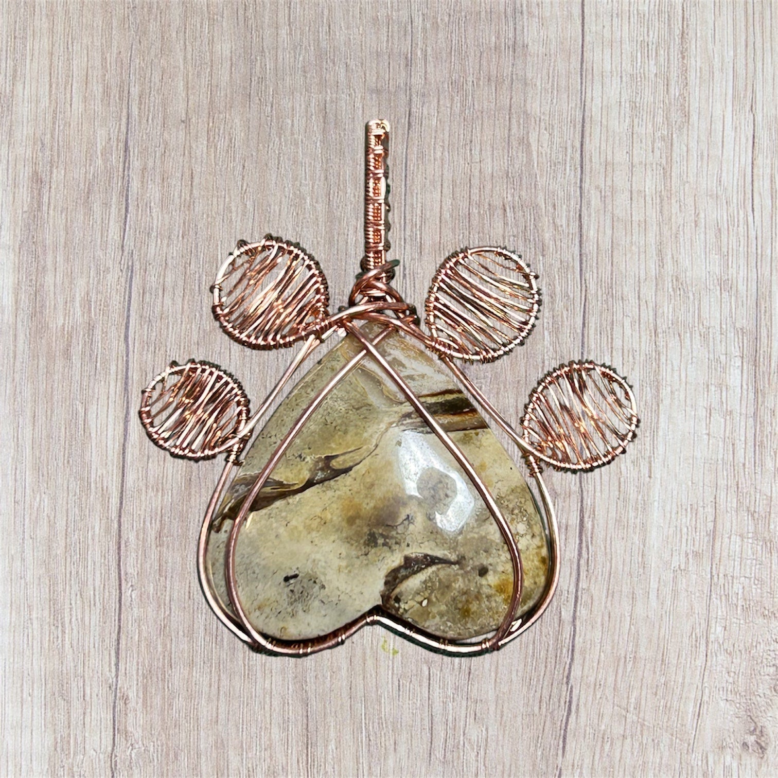 Copper wire wrapped Picture Jasper heart paw print pendant on wood background