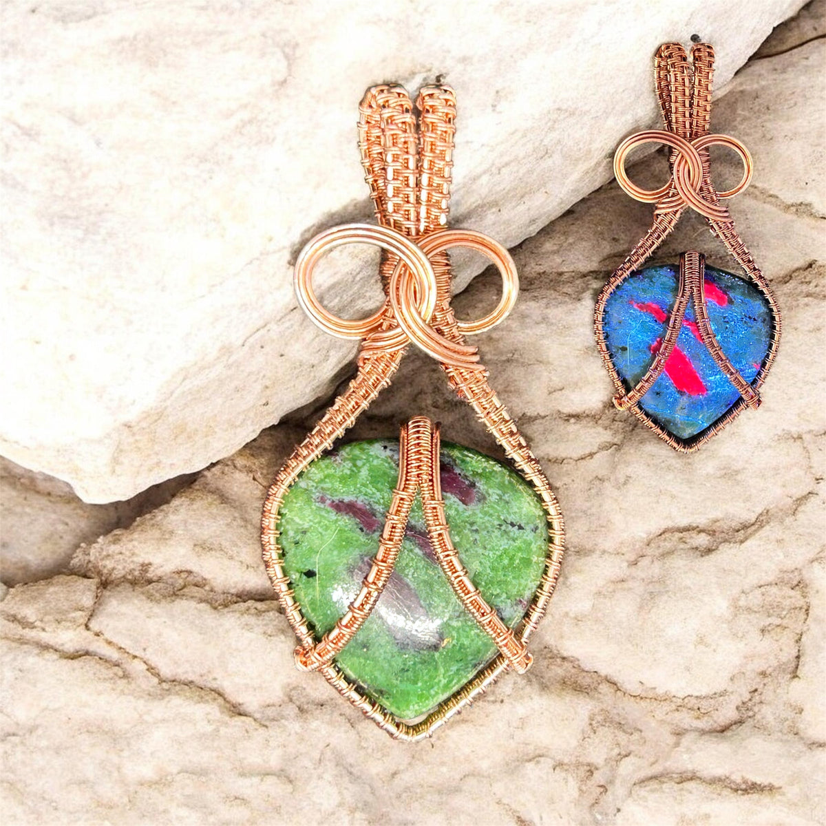 Copper wire wrapped Ruby Zoisite pendant shown in natural light (green and red) and UV light (blue and pink) on stone background