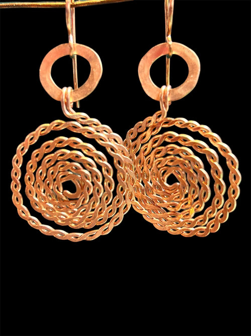 Copper twisted wire spiral earrings with hammered ring connectors on black background